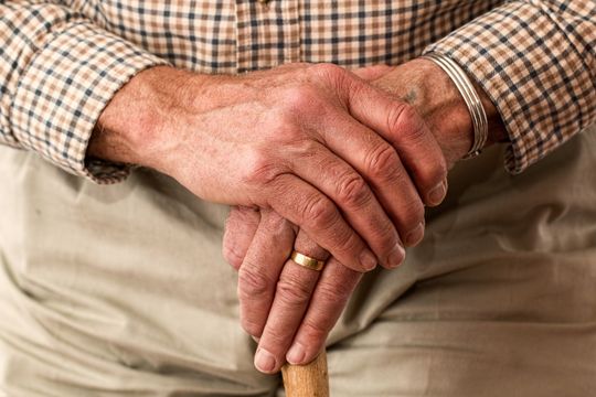 Manos de anciano descansando en garrota